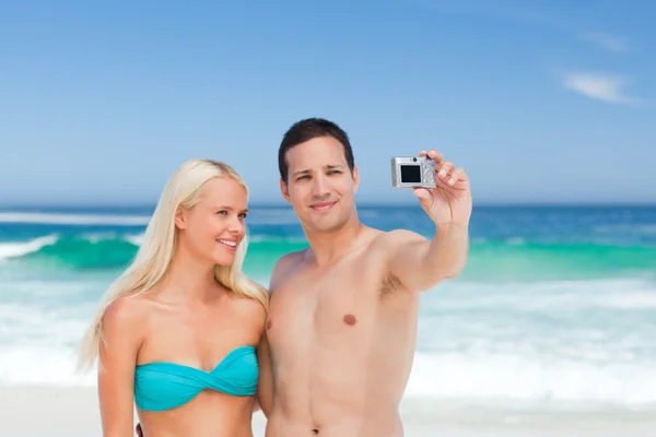 Casal tirando uma foto de si na praia — Fotografia de Stock