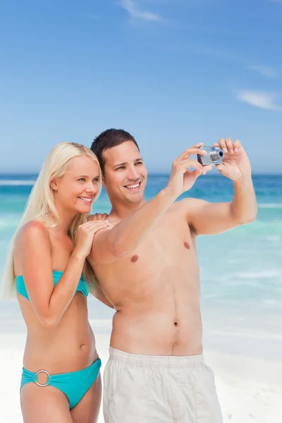 Casal tirando uma foto de si na praia — Fotografia de Stock