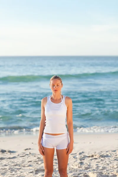 Kvinna utövar yoga på stranden — Stockfoto