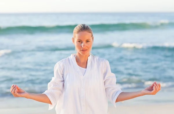 Активная женщина практикующая йогу на пляже — стоковое фото