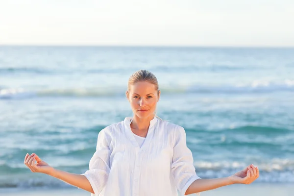 Mulher ativa praticando ioga na praia — Fotografia de Stock