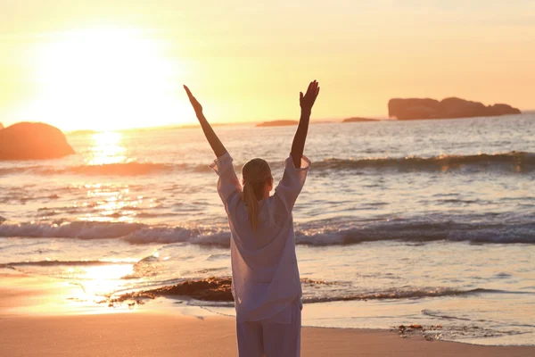 Žena cvičí jógu během západu slunce na pláži — Stock fotografie