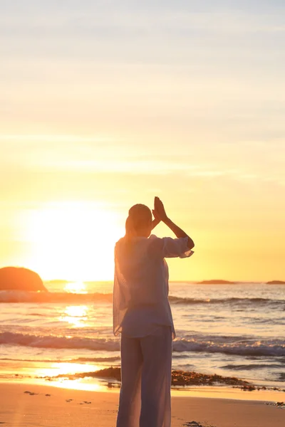 Kvinna utövar yoga under solnedgången på stranden — Stockfoto