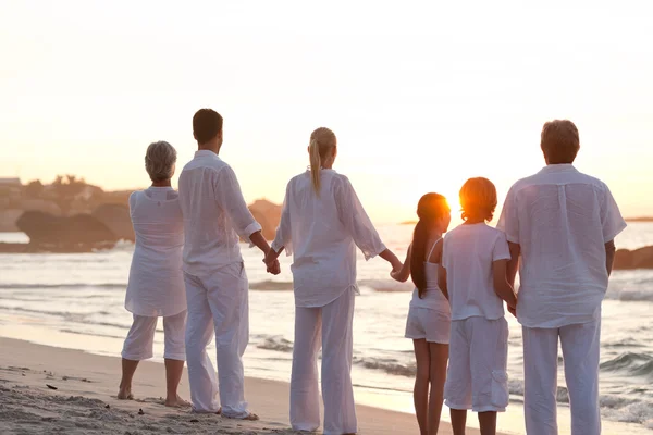 Familjen på stranden vid solnedgången — Stockfoto