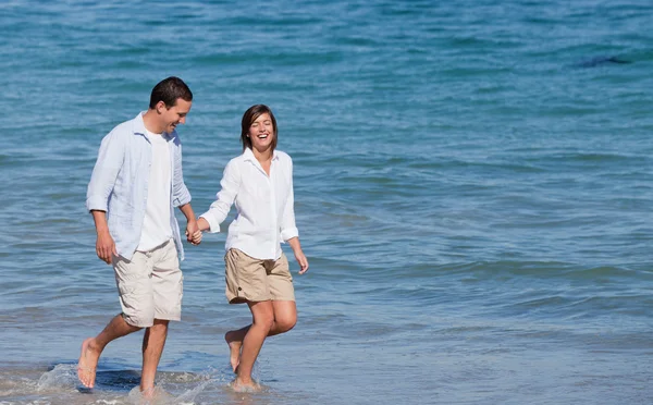 Casal andando na praia sob o sol — Fotografia de Stock