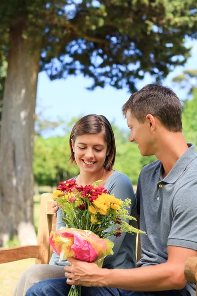 Joven hombre ofreciendo flores a su novia — Foto de Stock