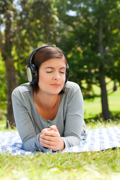 Vrouw luisteren naar muziek in het park — Stockfoto