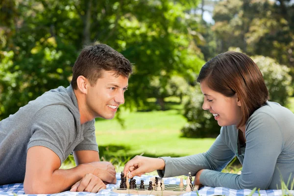 Пара играющая в шахматы в парке — стоковое фото