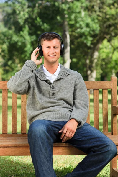 Young man listening to some music on the bench — Stock Photo, Image