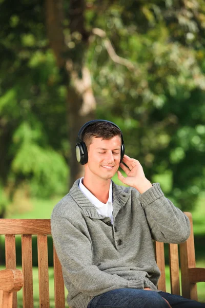 젊은 남자는 벤치에서 어떤 음악을 듣고 — 스톡 사진