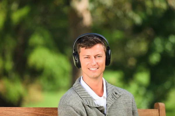 Fiatal ember hallgat zenét a padon — Stock Fotó