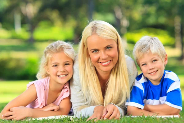 Mother with her children lying down in the park — Stock Photo, Image