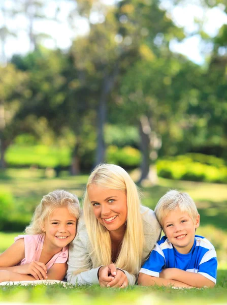 Mother with her children lying down in the park — Stock Photo, Image