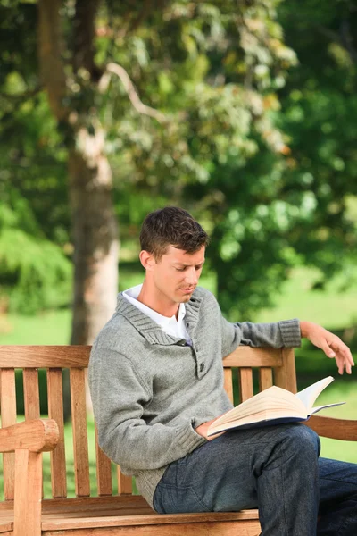 Genç adam bankta onun kitap okuma — Stok fotoğraf