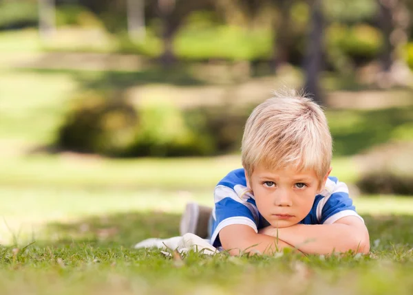 Chlapec vleže v parku — Stock fotografie