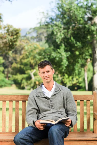 Young man reading his book on the bench — Stock Photo, Image