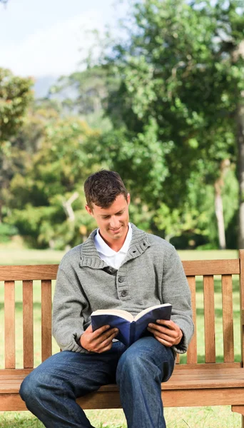 Muž čtení jeho knihy na lavičce — Stock fotografie