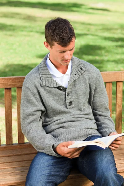 Человек, читающий свою книгу на скамейке — стоковое фото