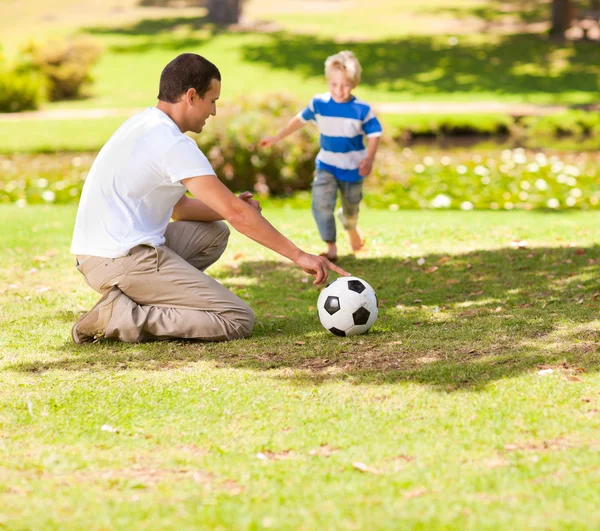 Отец играет в футбол со своим сыном — стоковое фото