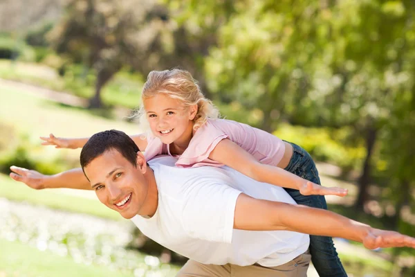 Маленькая девочка играет со своим отцом в парке — стоковое фото