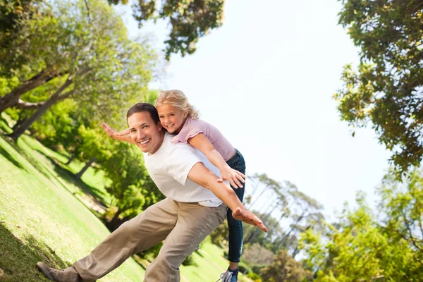 Маленькая девочка играет со своим отцом в парке — стоковое фото