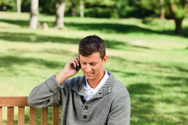 Young man phoning on the bench — Stock Photo, Image