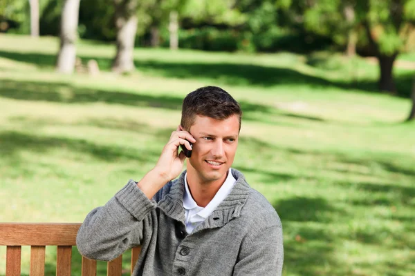 Young man phoning on the bench — Stock Photo, Image