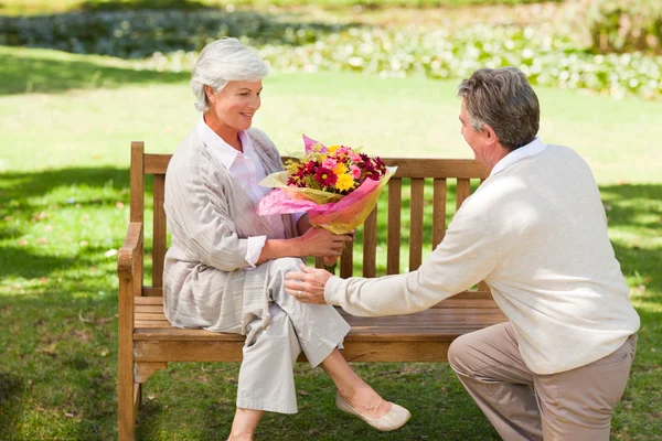 Senior man offering flowers to his wife — Stock Photo, Image