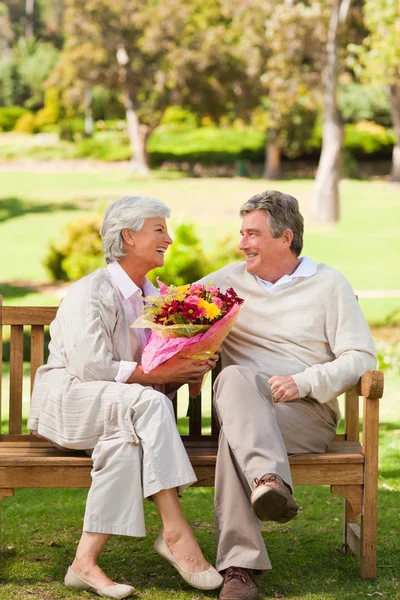 Hombre mayor ofreciendo flores a su esposa — Foto de Stock