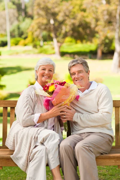 Uomo anziano che offre fiori a sua moglie — Foto Stock