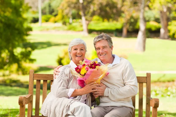 Äldre man erbjuder blommor till sin fru — Stockfoto