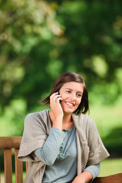 Beautiful woman phoning on the bench — Stock Photo, Image