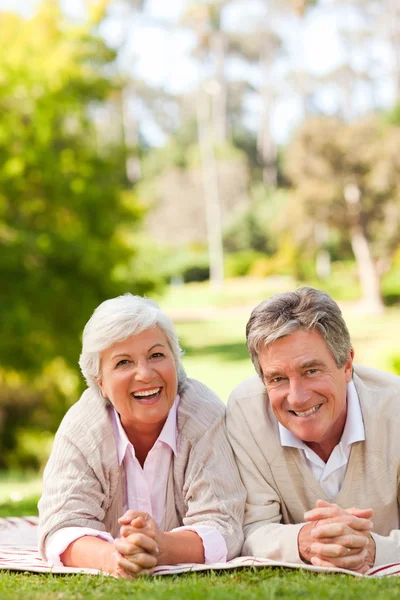 Mature couple lying down in the park — Stock Photo, Image
