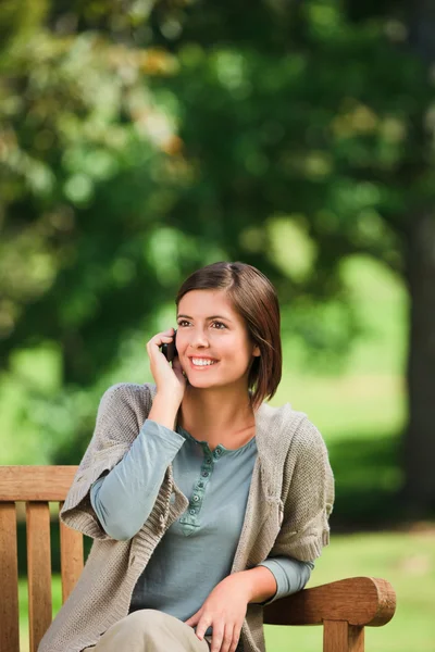 Schöne Frau telefoniert auf der Bank — Stockfoto