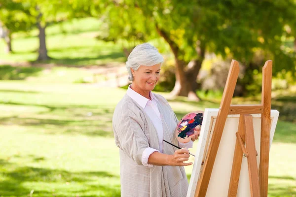 Äldre kvinna målning i parken — Stockfoto