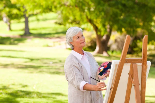 Starší žena, malování v parku — Stock fotografie