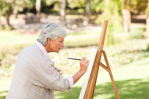 Volwassen vrouw schilderij in het park — Stockfoto