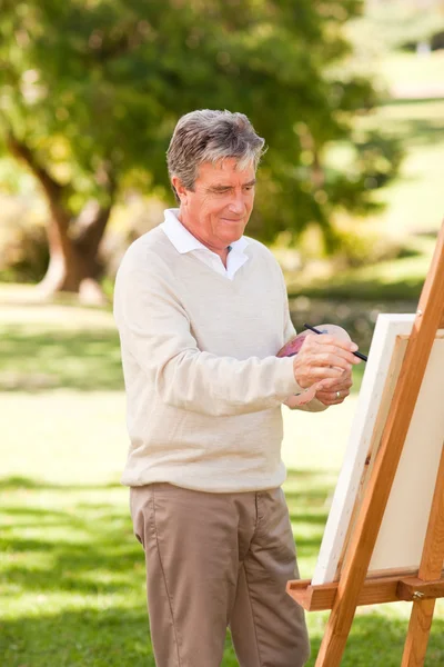 Elderly man painting in the park — Stock Photo, Image