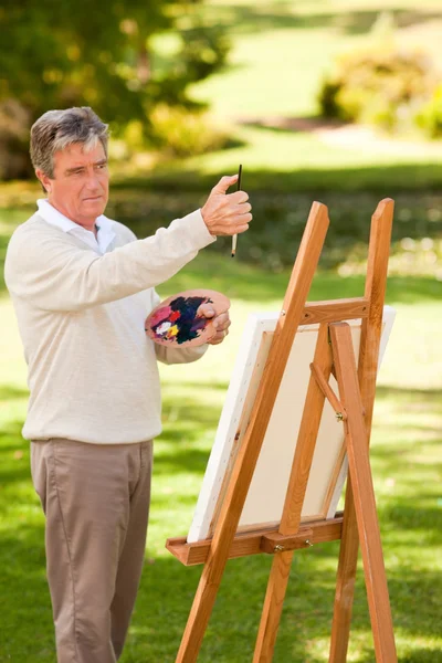 Літній чоловік малює в парку — стокове фото