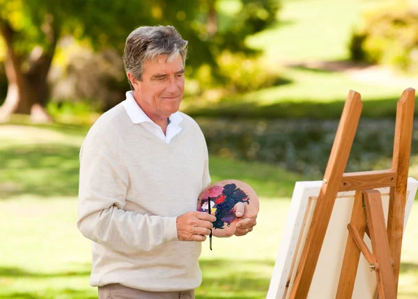 Oudere man schilderij in het park — Stockfoto