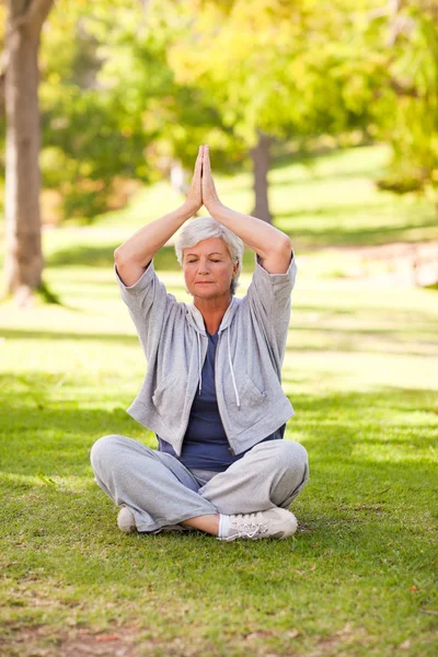 Mulher sênior praticando ioga no parque — Fotografia de Stock