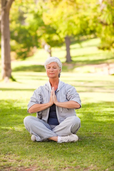 Senior woman practicing yoga in the park — Stock Photo, Image