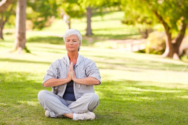 Äldre kvinna utövar yoga i parken — Stockfoto
