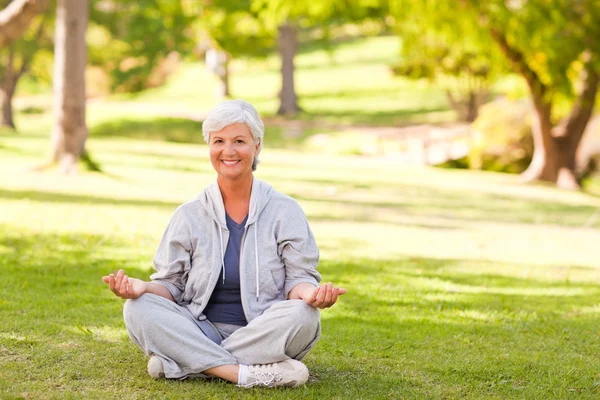 Mature woman practicing yoga in the park — Stock Photo, Image
