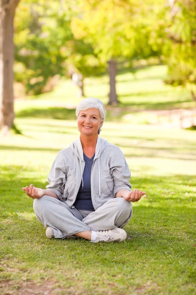 Parkta yoga yapan olgun bir kadın. — Stok fotoğraf