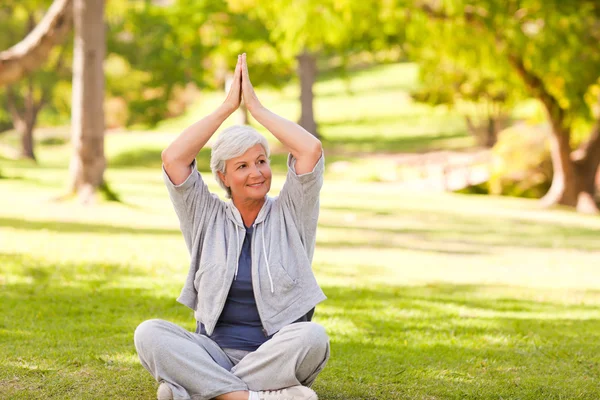 Reife Frau praktiziert Yoga im Park — Stockfoto