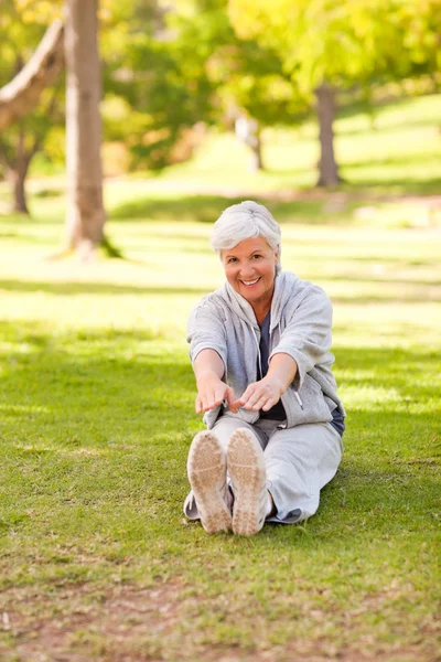 Ушедшая на пенсию женщина делает растяжку в парке — стоковое фото