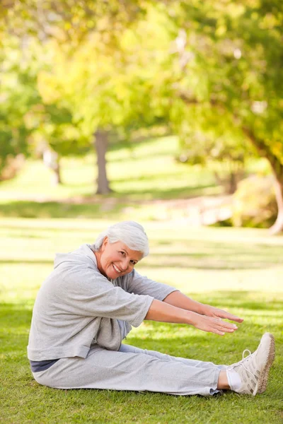 Ушедшая на пенсию женщина делает растяжку в парке — стоковое фото