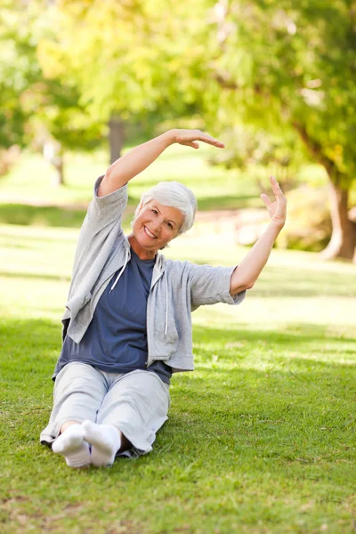 Äldre kvinna gör henne sträcker sig i parken — Stockfoto