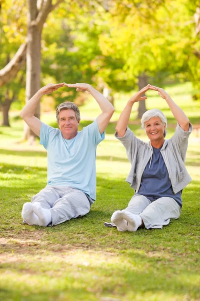 Äldre par gör sina sträckor i parken — Stockfoto